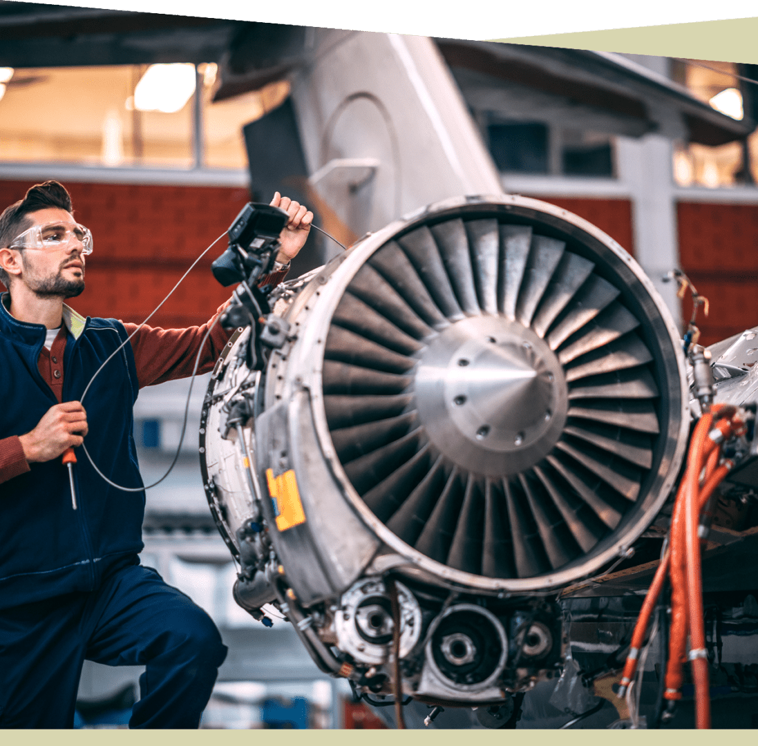 Group 6 A certified technician in safety glasses meticulously inspects a jet engine with a borescope, ensuring it meets all mechanic certification criteria in an industrial setting.